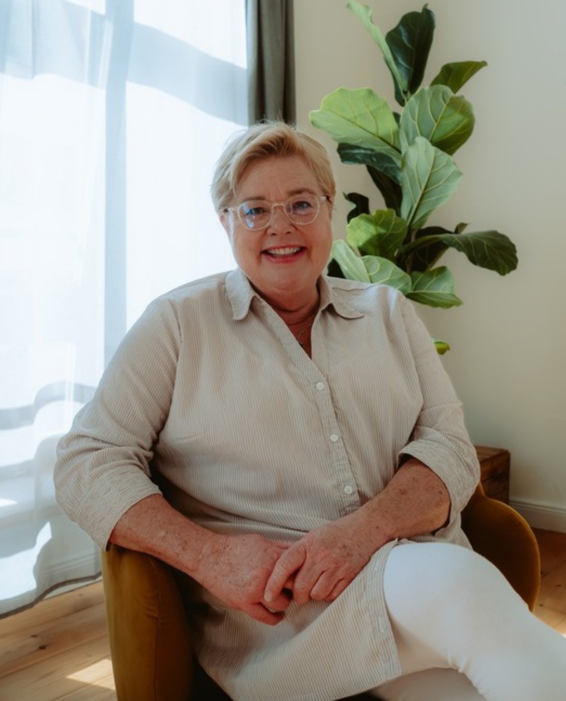 Ulrike Post sitzt in einem Sessel und schaut freundlich in die Kamera